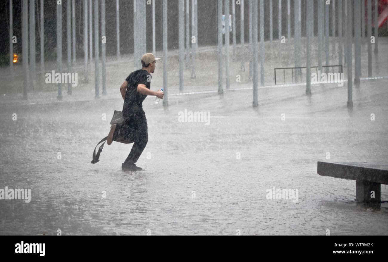Hombre corriendo en la lluvia en la calle en la ciudad Foto de stock