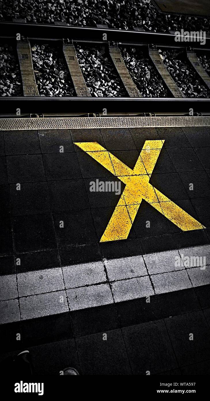 Un alto ángulo de visualización de la Cruz Amarilla signo en la plataforma de estación de ferrocarril Foto de stock