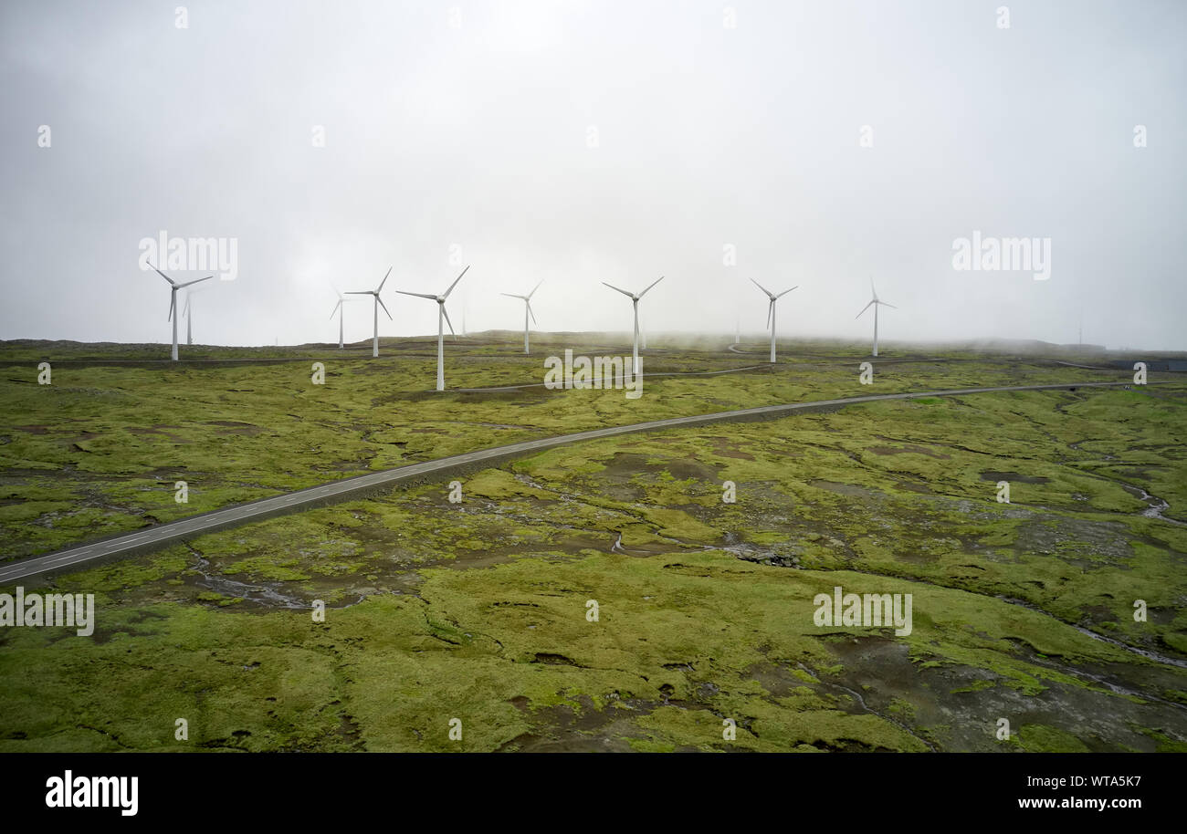 Drone vista de modernos molinos de viento en funcionamiento misty verde llanura en sombrío día Foto de stock