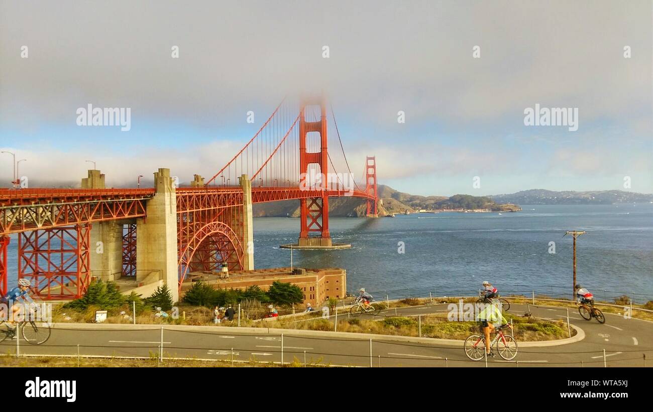 Bicicleta Equitación ciclista en la carretera por debajo el puente Golden Gate de la Bahía contra el cielo Foto de stock