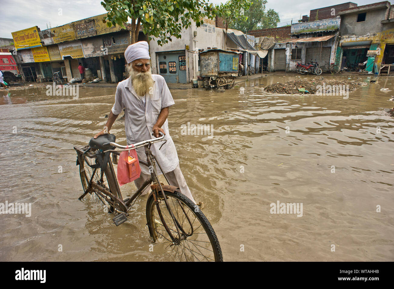 Hombre Sikh llevar su bicicleta en las calles en un día de inundación Foto de stock