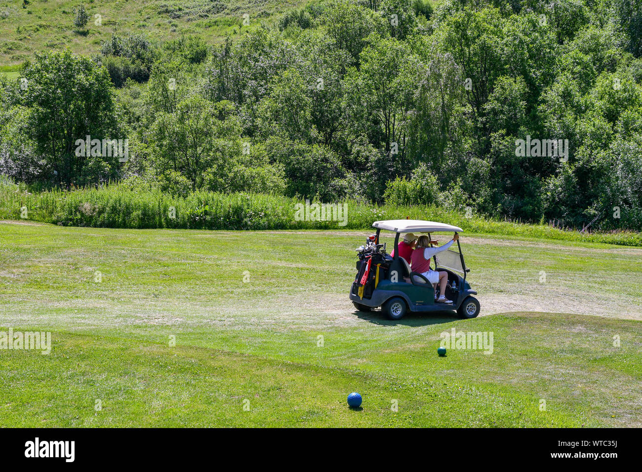 Una pareja de mediana edad en un carro de golf en un campo de golf en verano, Golf Club Courmayeur y Grandes Jorasses, Val Ferret, Courmayeur, Valle de Aosta, Italia Foto de stock