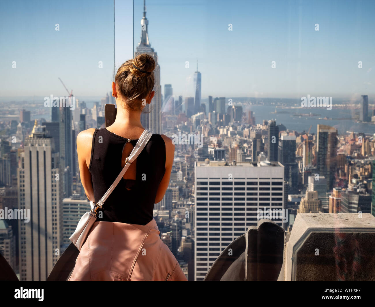 Linda chica tomando fotos de los rascacielos de Manhattan con el Empire State Building en frente, Nueva York, EE.UU. Foto de stock
