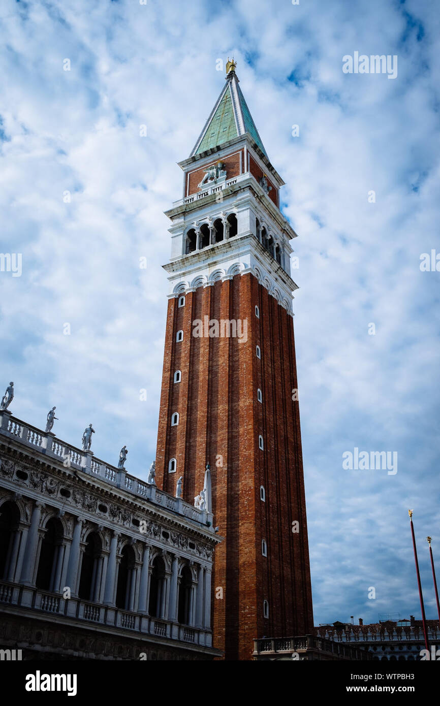 Ángulo de visión baja del campanario de la plaza San Marco contra el azul cielo nublado Foto de stock