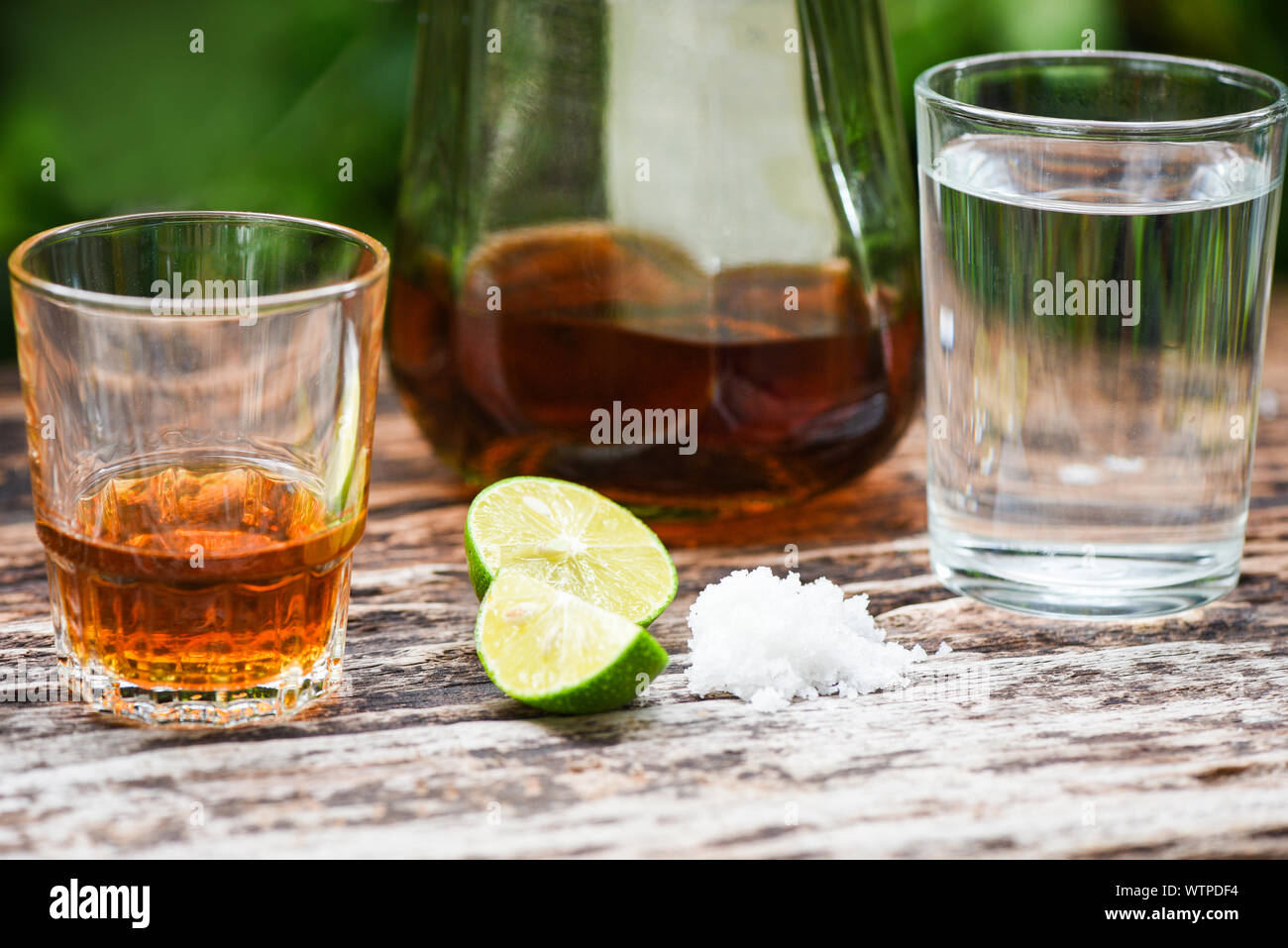 Las bebidas alcohólicas y limón Sal sobre fondo de madera rústica / brandy  en un vaso con alcohol y agua - botellas de vodka ron tequila de coñac y  whisky co Fotografía