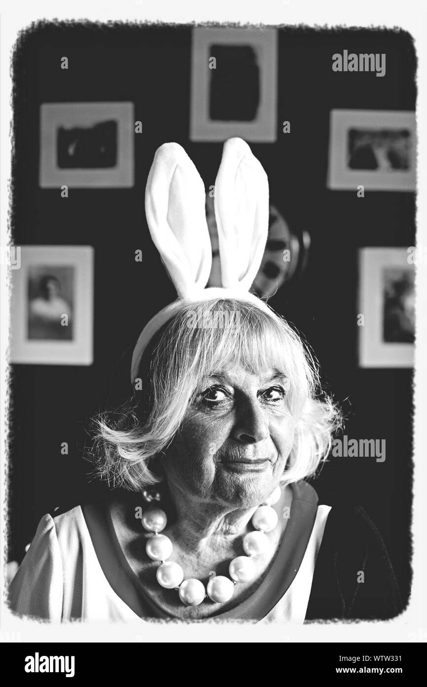 Retrato de mujer vistiendo trajes Senior de orejas de conejo en casa Foto de stock