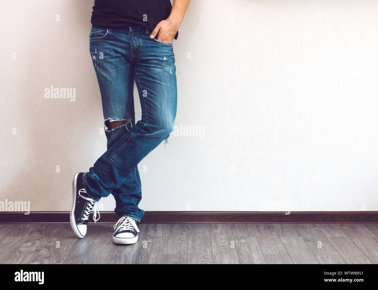 Moda joven hombre en las piernas de los pantalones vaqueros y zapatillas  sobre piso de madera Fotografía de stock - Alamy
