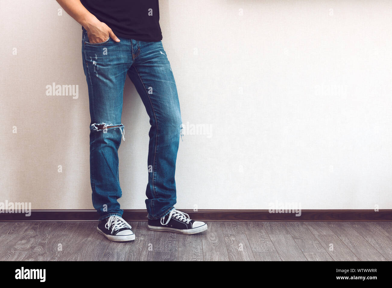 Moda joven hombre en las piernas de los pantalones vaqueros y zapatillas  sobre piso de madera Fotografía de stock - Alamy