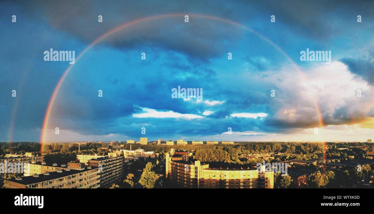 Paisaje urbano contra Rainbow y cielo azul Foto de stock
