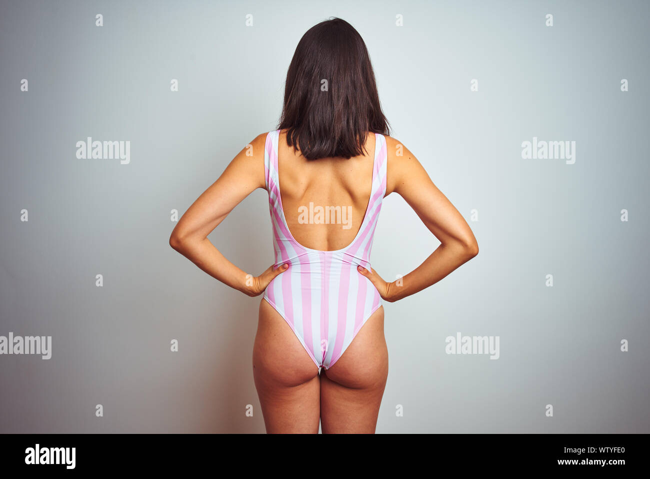 Hermosa joven mujer vistiendo Bañadores Bañador rosa rayas sobre  antecedentes aislados de pie mirando hacia atrás lejos con los brazos sobre  el cuerpo Fotografía de stock - Alamy