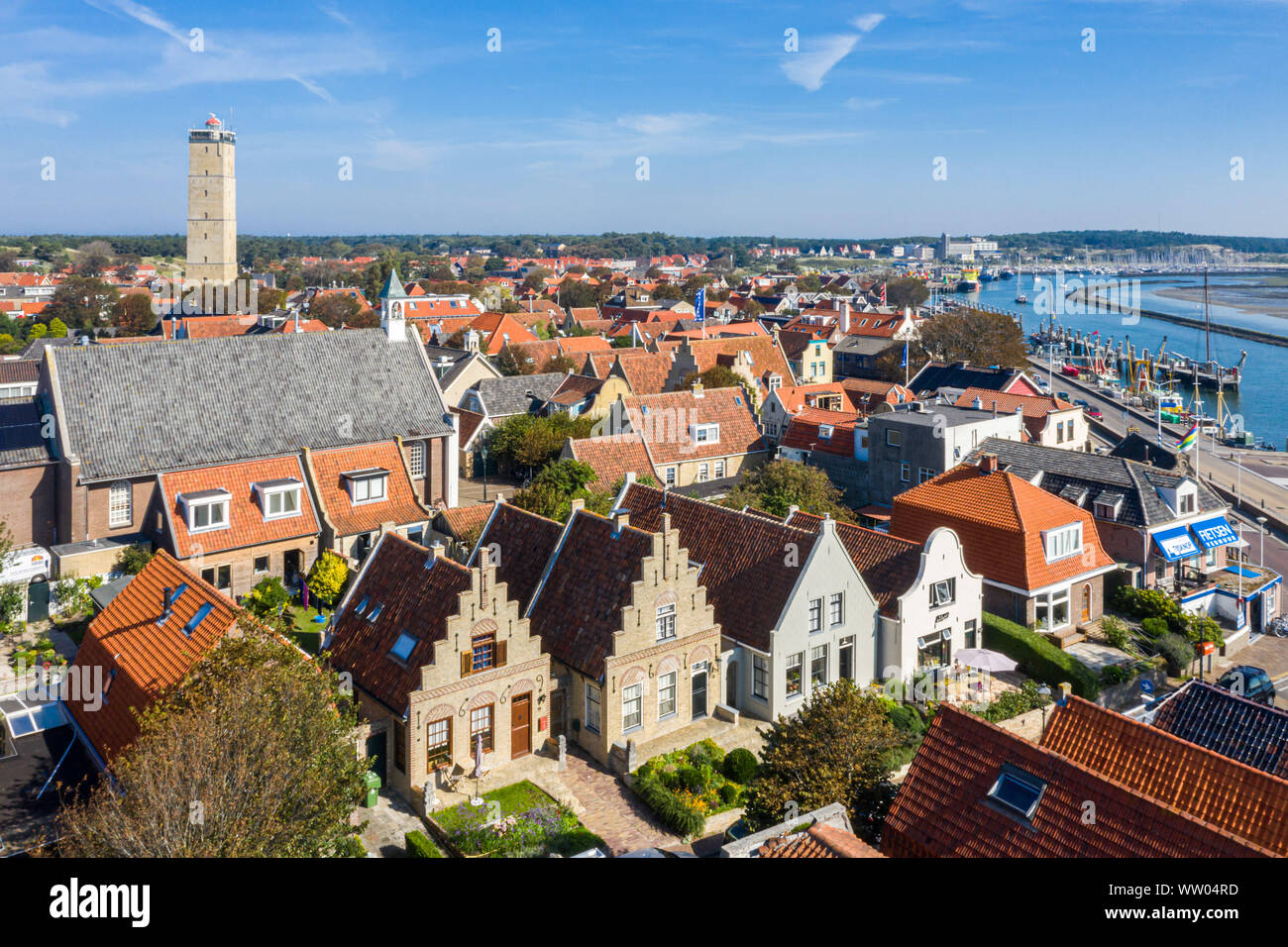 Países Bajos, Terschelling - Agosto 25, 2019: faro Brandaris y Westerkerk, puerto y casas históricas de la ciudad West-Terschelling. Aguas superficiales Foto de stock