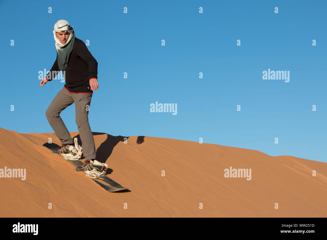 Un hombre con un pañuelo en la cabeza practicando sandboard en las dunas  del desierto de Erg Chebbi Fotografía de stock - Alamy