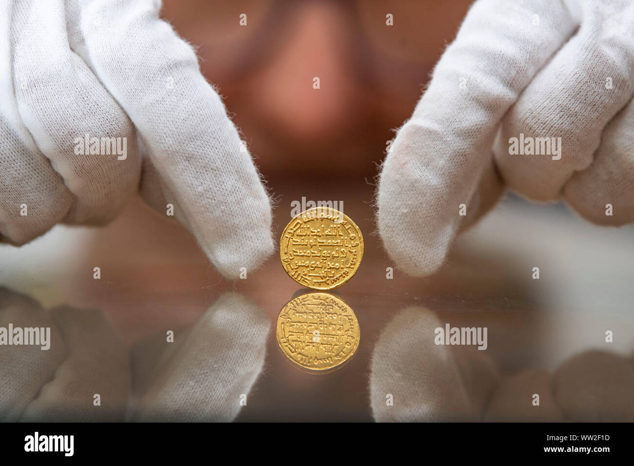 Un miembro del personal a Morton & Eden tiene una extremadamente raro Islámicos tempranos de moneda de oro que se espera obtener de ??1,4m en una subasta en Londres. PA la foto. Imagen Fecha: jueves 12 de septiembre de 2019. Una medición de 20mm de ancho, aproximadamente del tamaño de un moderno ??1 pieza, es uno de los más raros del mundo islámico más valiosas y monedas de oro de la primera dinastía Omeya de Islam, el dinar de oro fecha 105h (723AD). Crédito de la foto debe leer: Victoria Jones/PA Cable Foto de stock