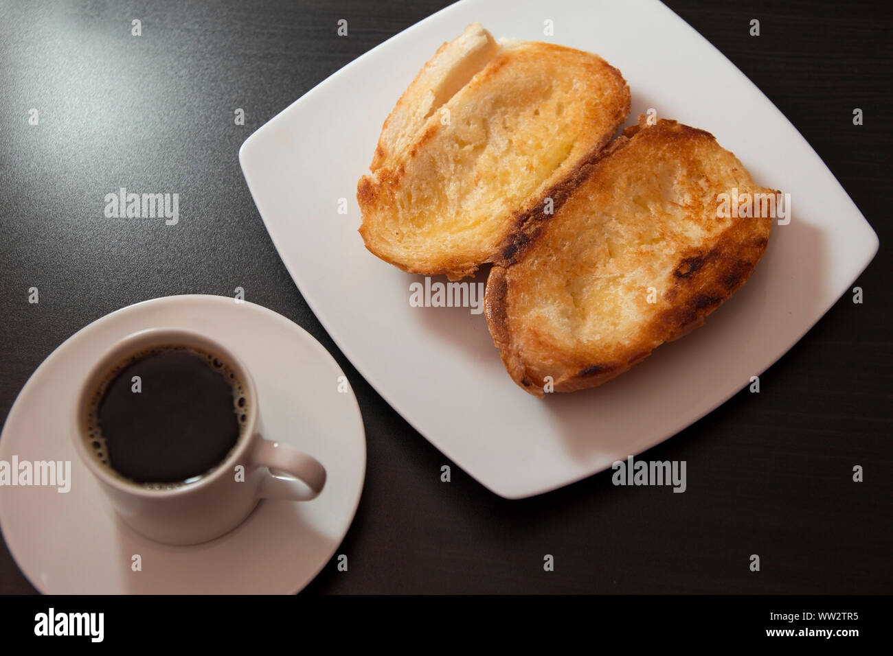 Pan francés tostado con mantequilla en la placa con el café. Pao na chapa tradicional desayuno brasileño. Descripción general Foto de stock