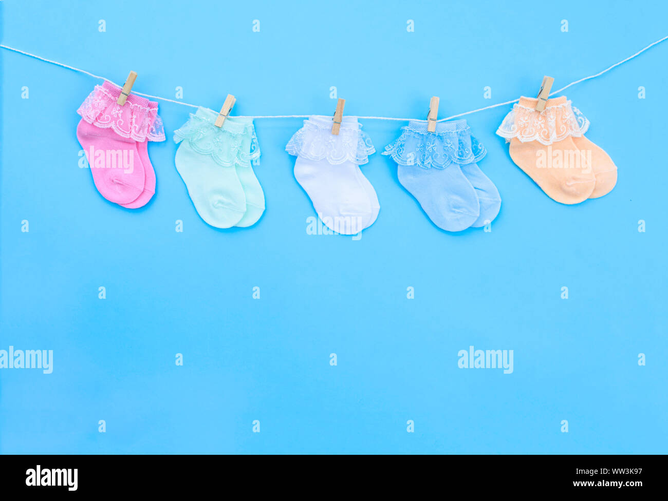 Colorido lindo bebé calcetines colgando en el tendedero sobre fondo azul. Accesorios  para el bebé. Sentar planas Fotografía de stock - Alamy