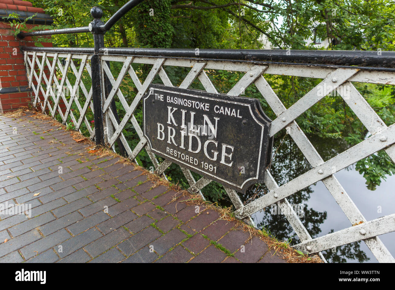 Horno Puente, una carretera, un puente sobre el canal de Basingstoke con una placa con el nombre de St John's Village, cerca de Woking, Surrey, sudeste de Inglaterra, Reino Unido. Foto de stock