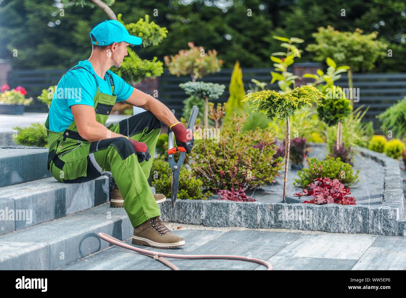 Jardinero profesional del Cáucaso en su 30s y su recién desarrollado jardín residencial> Industria de paisajismo. Foto de stock