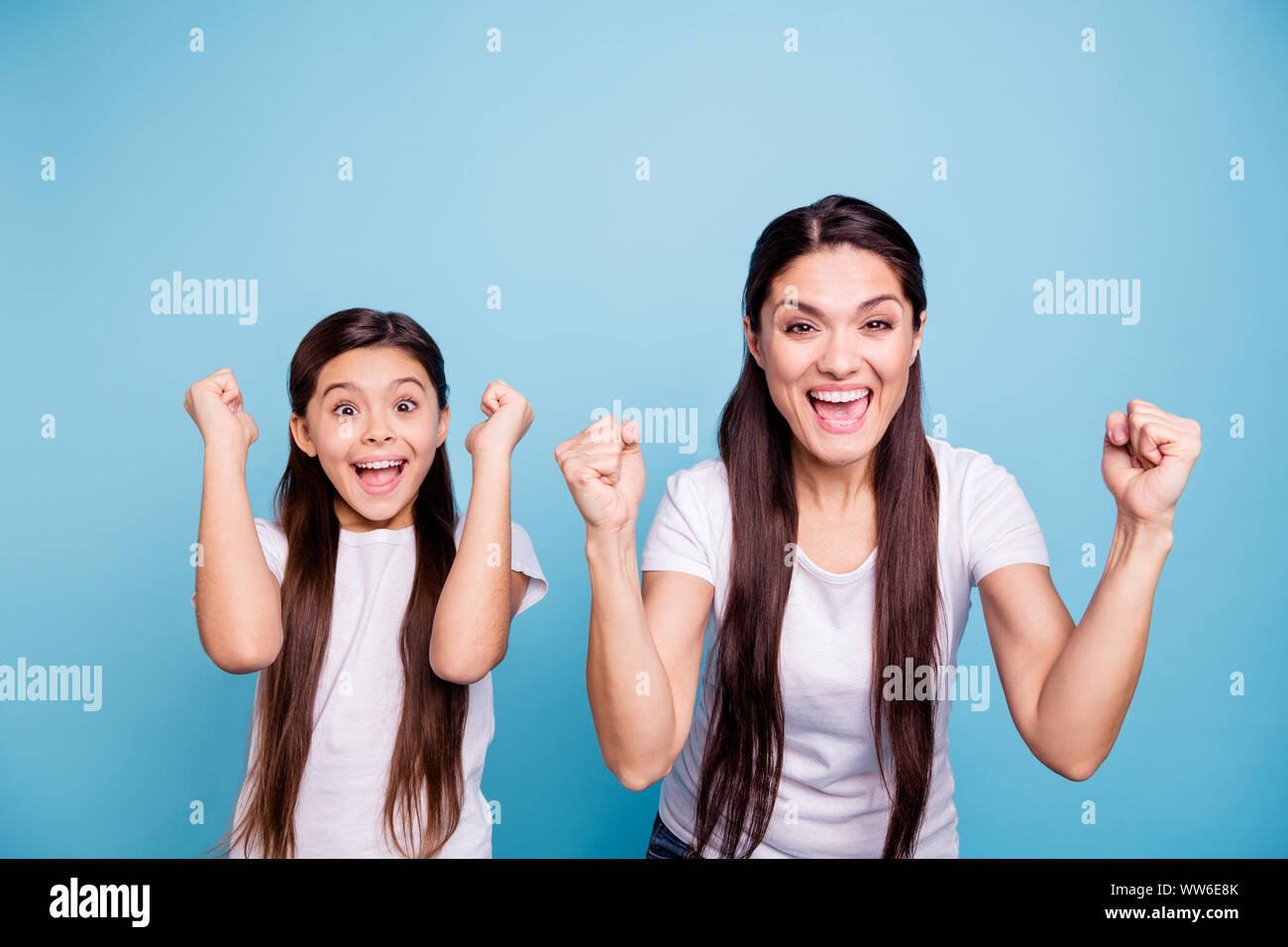 Cerrar Foto alegrar a dos personas de pelo marrón mum pequeña hija manos brazos alegra aire gritar reír risa hinchas de fútbol objetivo encantado de vestir de blanco Foto de stock