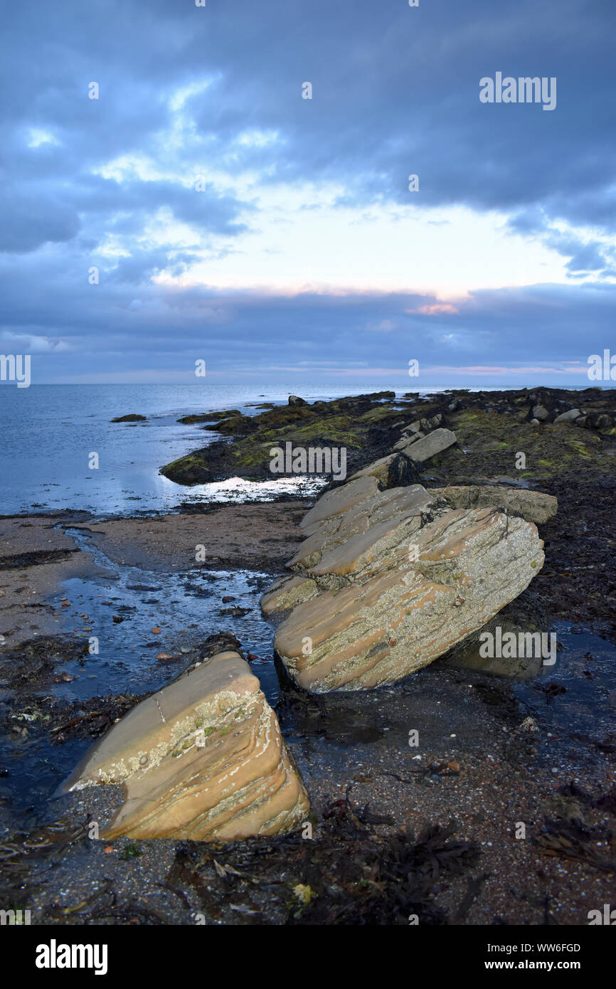 Grandes rocas en la playa tomadas al anochecer, orientación vertical. Tomadas cerca de Wick, Highlands Escocesas, costa norte 500 NC 500 route Foto de stock