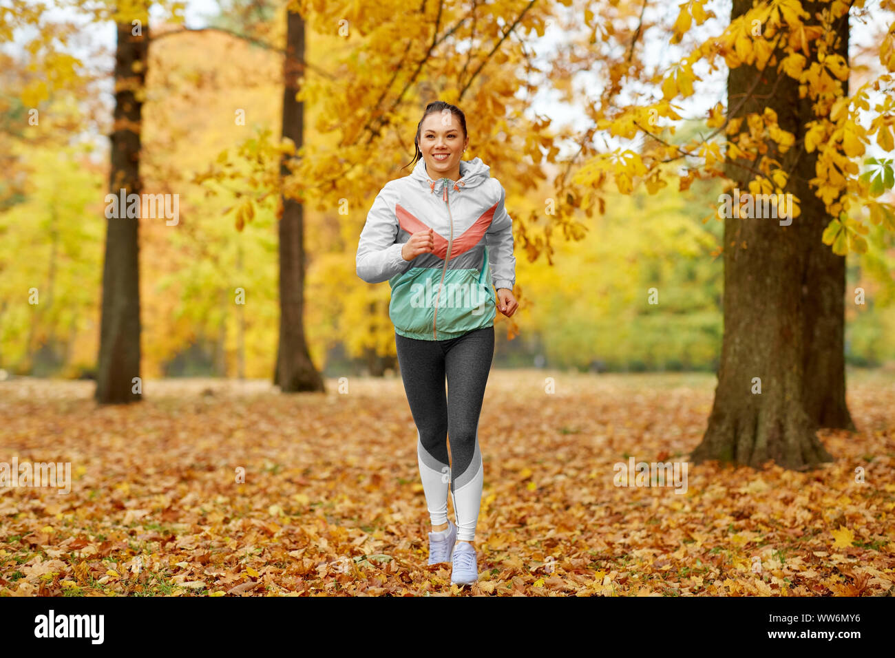 Mujer joven corriendo en el parque de otoño Foto de stock