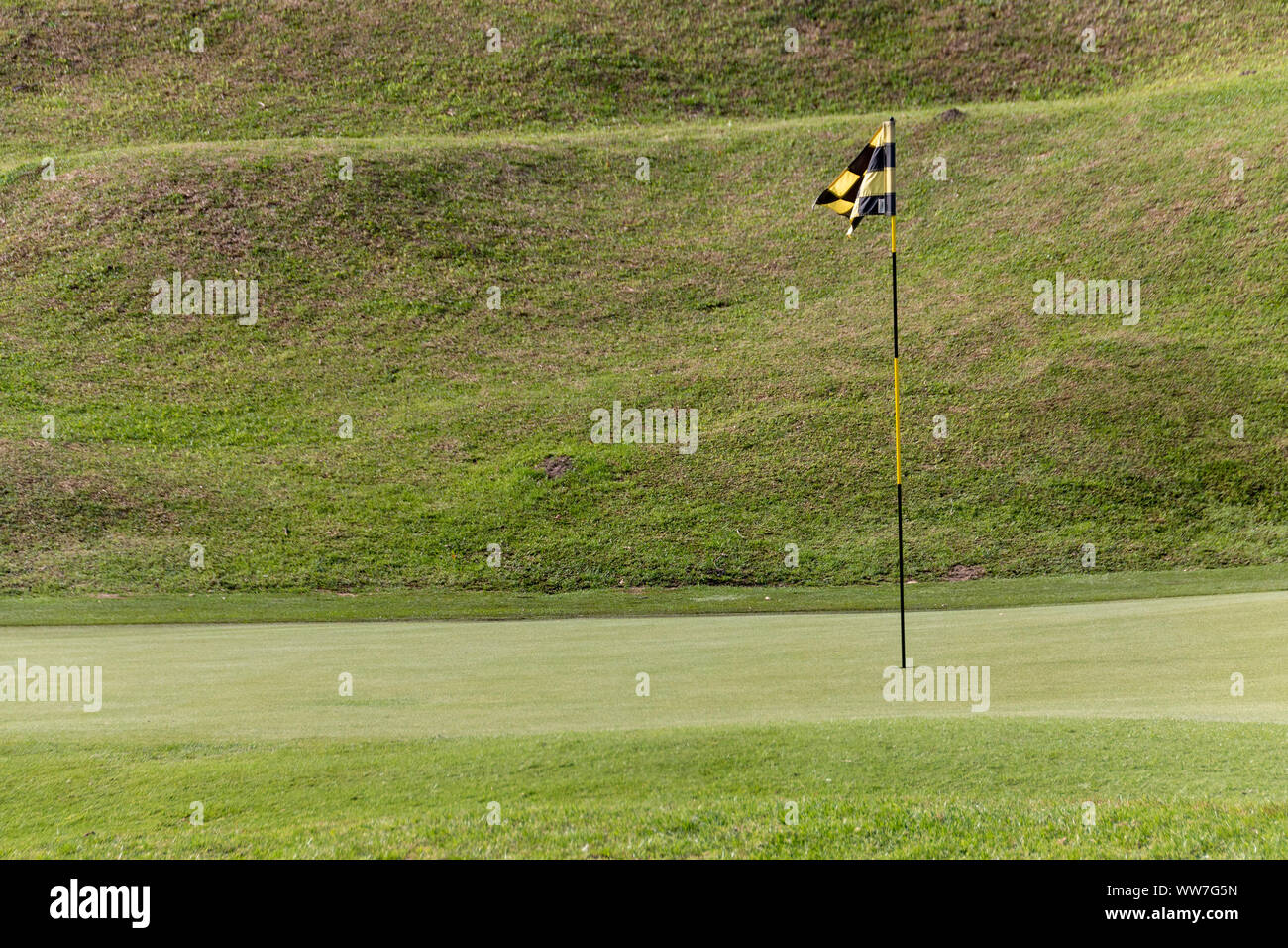 Una vista de cerca de un mástil de bandera amarilla y negra, en el verde en un agujero en un campo de golf Foto de stock