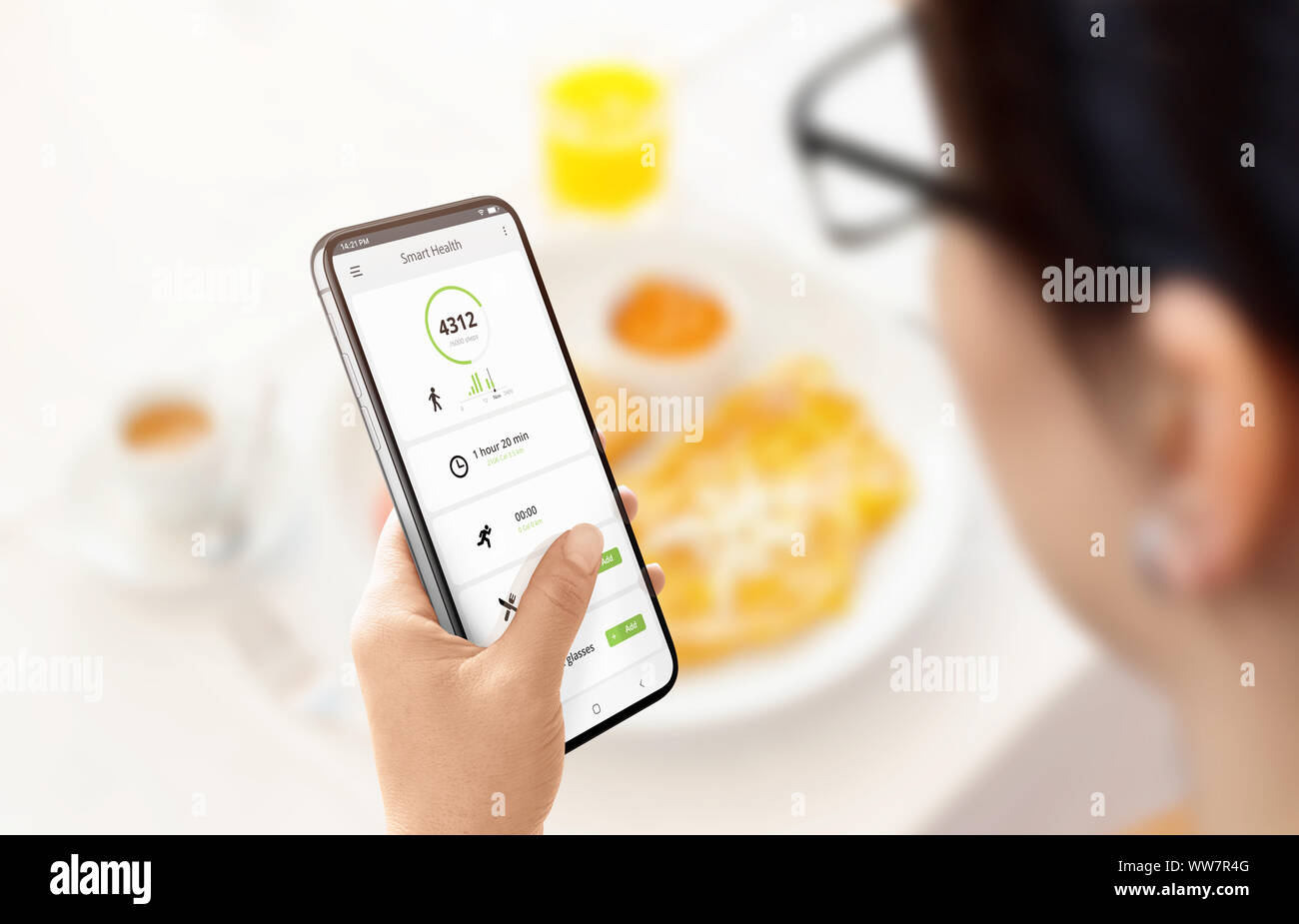 Chica calcula las calorías quemadas y consumidas en la app de teléfono inteligente moderno. Almuerzo en el fondo. Concepto. Foto de stock