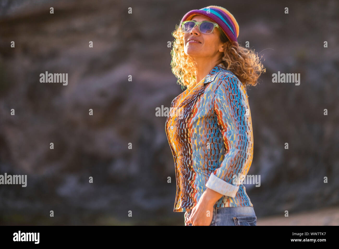 Alegre feliz atractiva mujer caucásica edad media sonrisa y mirar en el aire disfrutando del buen clima y el sol. la felicidad en actividad de ocio al aire libre y se viste como hippie de color Foto de stock