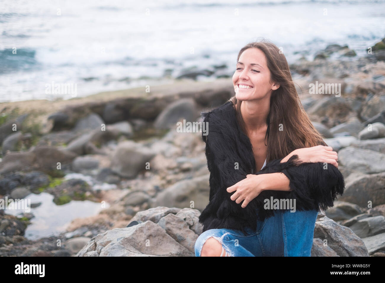 Indie joven mujer caucásica para disfrutar de la naturaleza y la libertad  solamente en las rocas en la playa, en el fondo del océano, ropa casual y  wanderlust concepto Fotografía de stock -