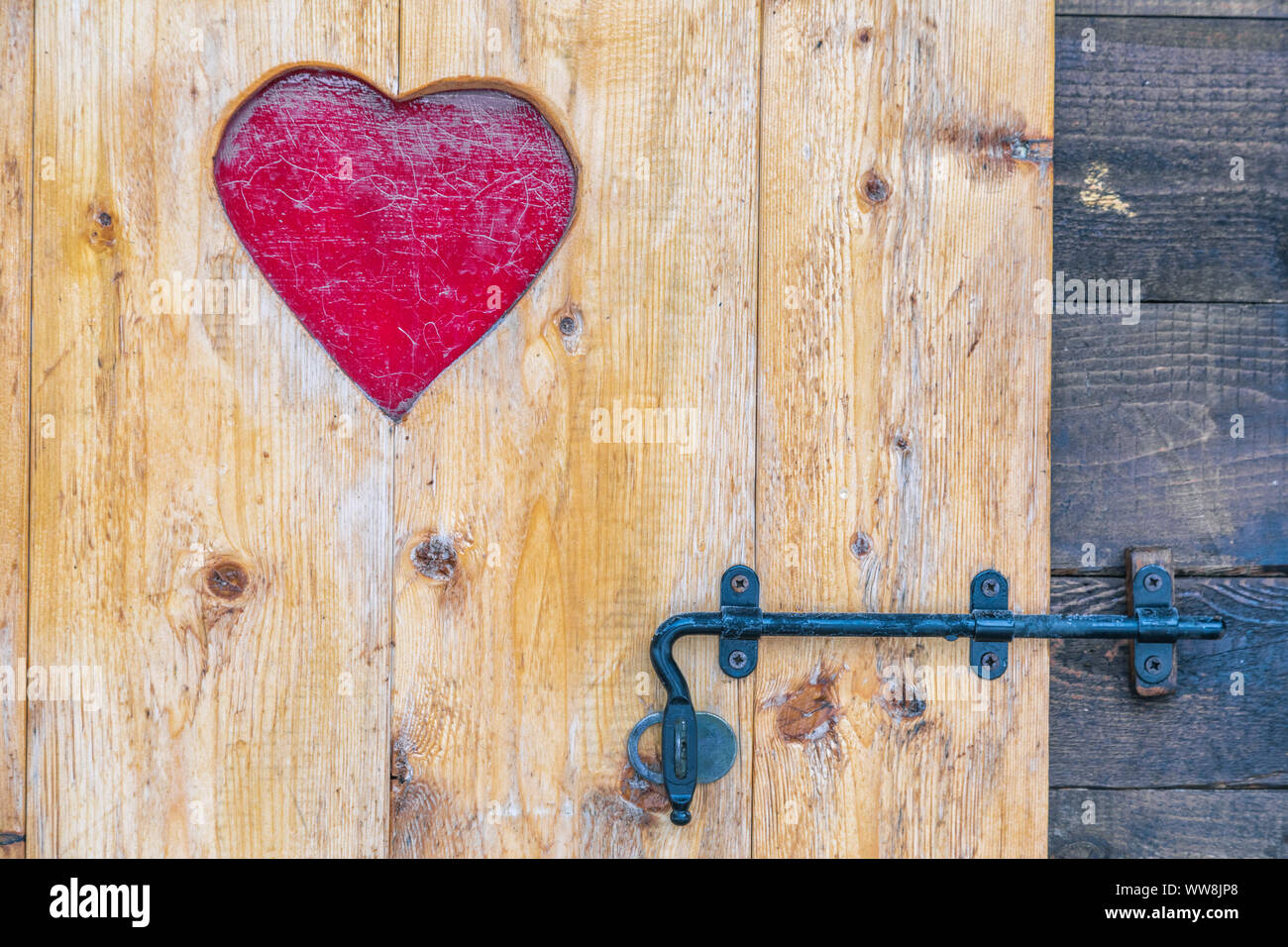 Puerta de madera rústica con corazón decoración, cerrada con pestillo Foto de stock