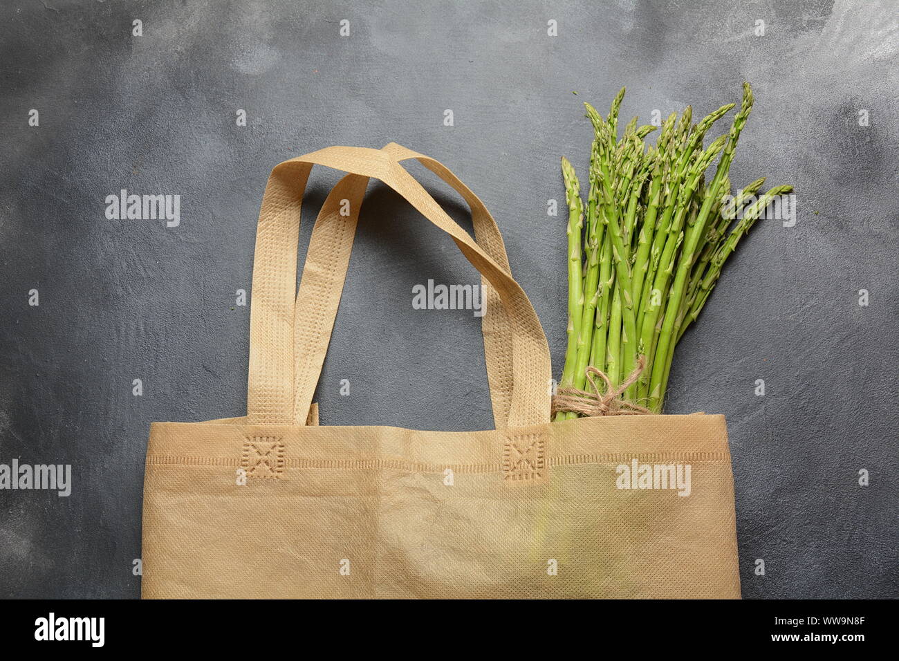 Bolsa de productos textiles reutilizables sin residuos llena de espárragos verdes y perejil Foto de stock