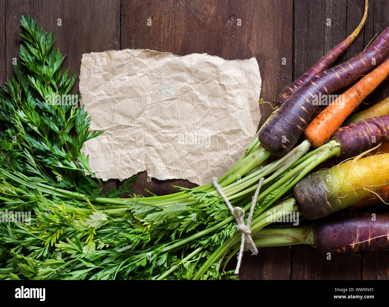 Rainbow zanahorias frescas orgánicas y papel artesanal en madera Foto de stock