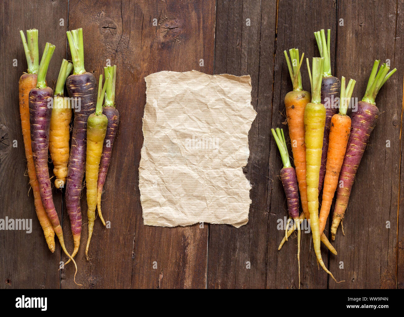 Rainbow zanahorias frescas orgánicas y papel artesanal en madera Foto de stock