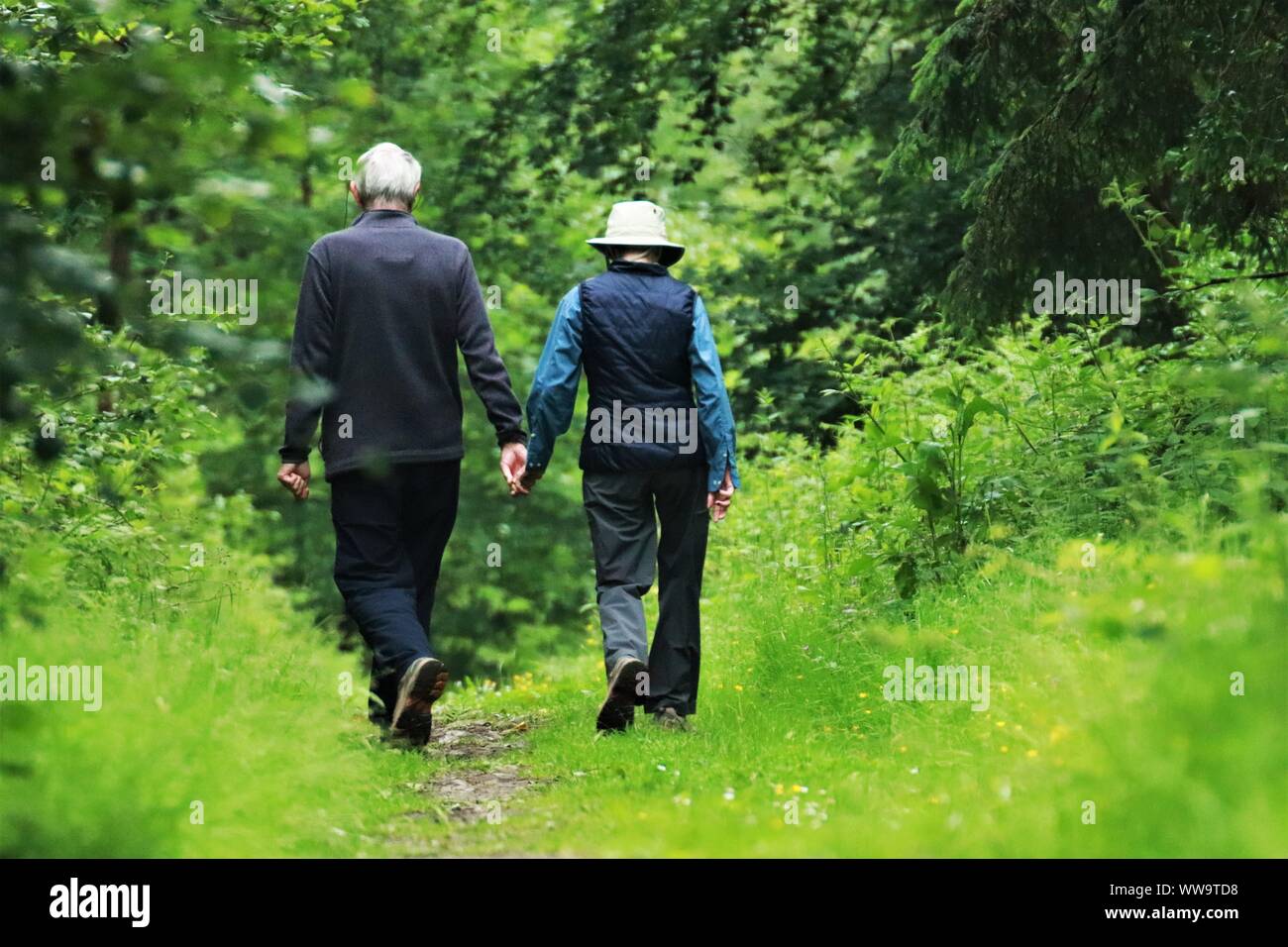 Viejo hombre y mujer caminando y tomándose de la mano. Foto de stock