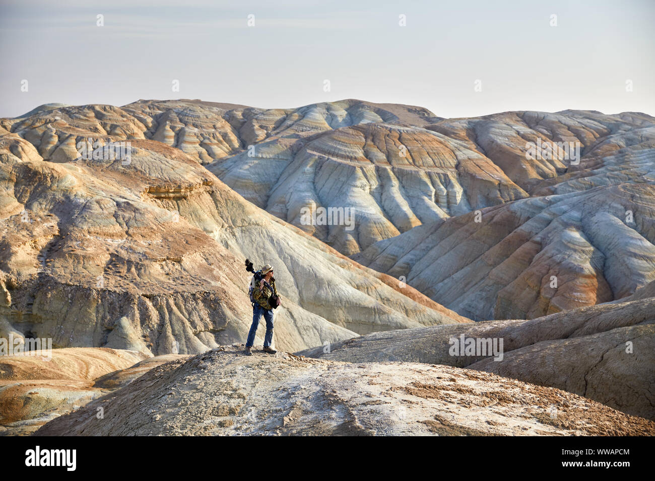 Turista con cámara y mochila en las montañas del desierto surrealista Foto de stock