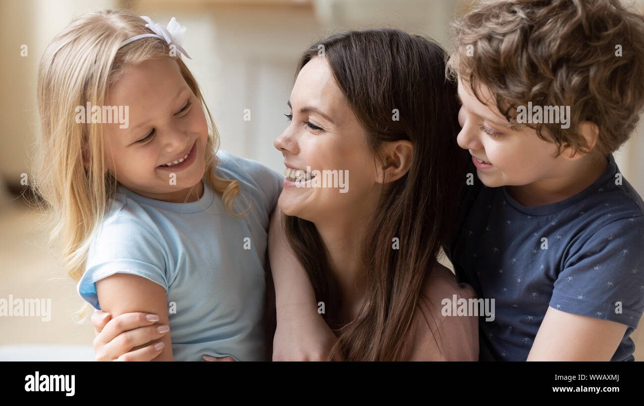 Alegría joven mamá comunica con dos niños pequeños. Foto de stock