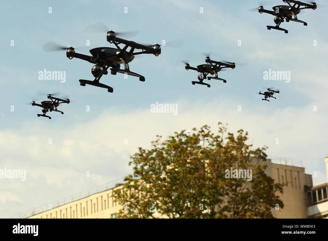 Enjambre de aviones no tripulados (UAV) Quadcopters aviones en el aire sobre la ciudad Foto de stock