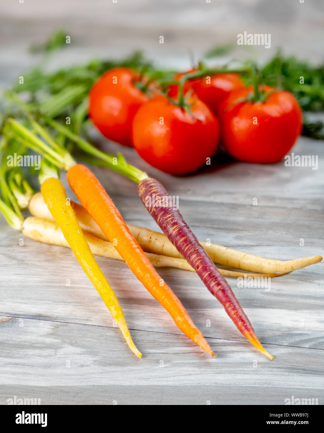 Deliciosas verduras de zanahorias y tomates sobre una tabla de madera Foto de stock