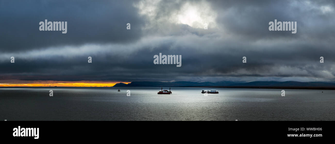 Paisaje Panorámico de tres naves en el mar de Bering y la isla San Lorenzo en el fondo en el atardecer - Sunset en un día tempestuoso, Alaska. Foto de stock