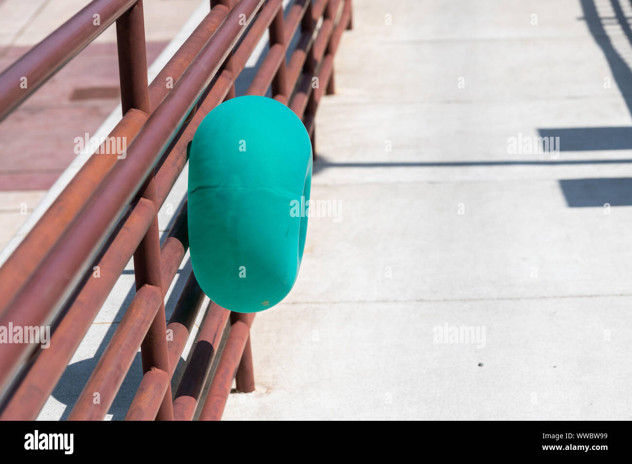 Uno de anillos o agujero rosquilla verde colorido globo adherido a la reja por la acera de la calle Foto de stock