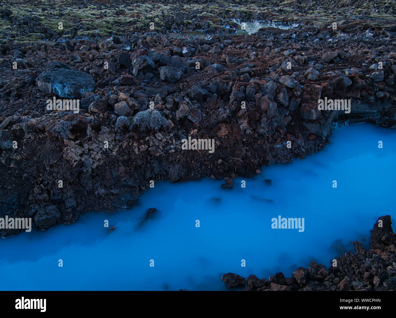 Un paisaje de lava con el agua de la Laguna Azul en Islandia Foto de stock