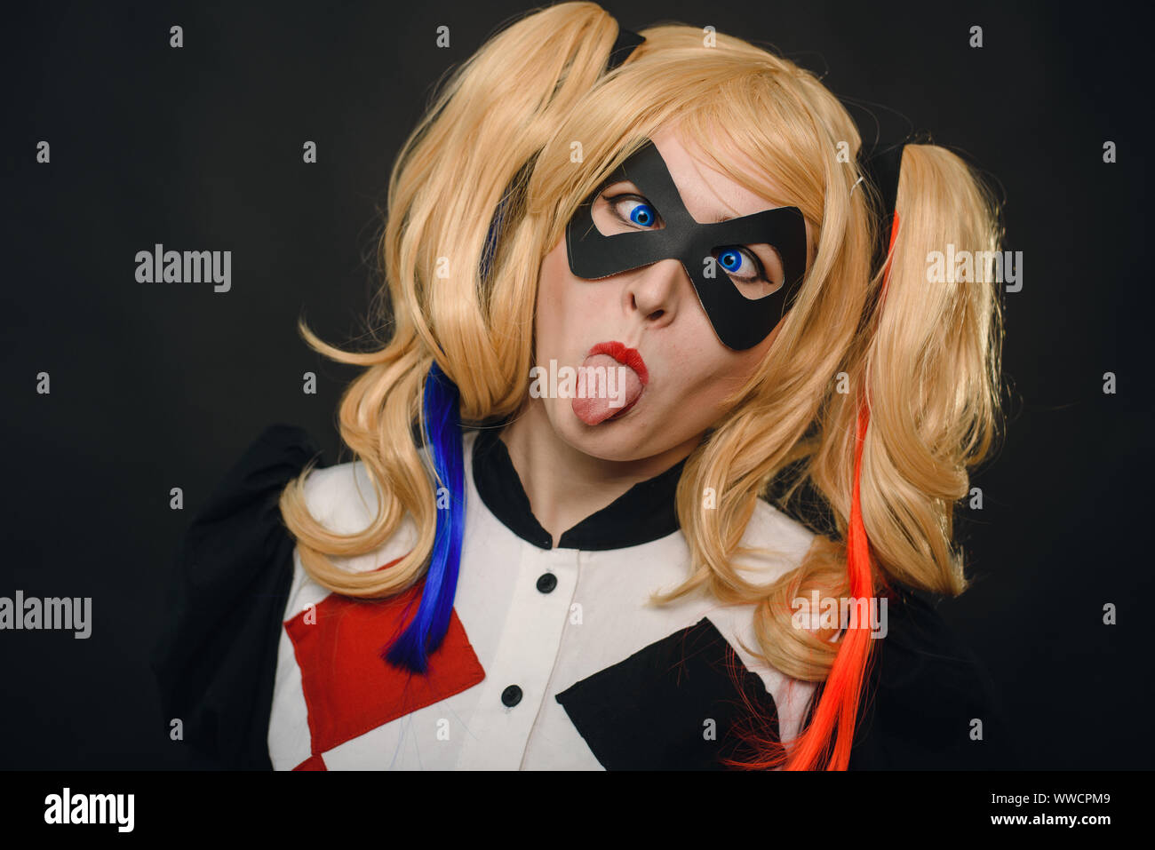 Chica en traje de Harley Quinn. Ella se levanta con un bate y lame el bat.  Cerca. Cosplay Fotografía de stock - Alamy