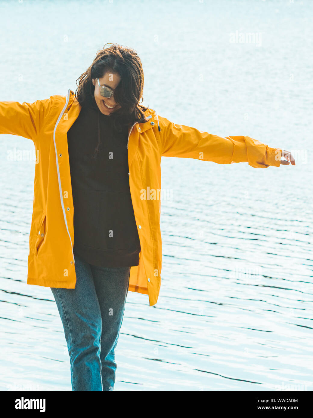 Mujer joven en amarillo impermeable en la parte delantera del agua Foto de stock