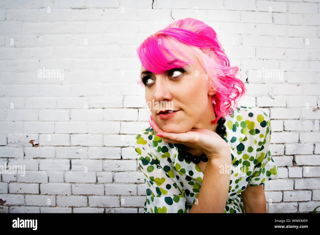 Mujer con pelo de color rosa en la parte frontal de la pared de ladrillo  pintado de blanco Fotografía de stock - Alamy