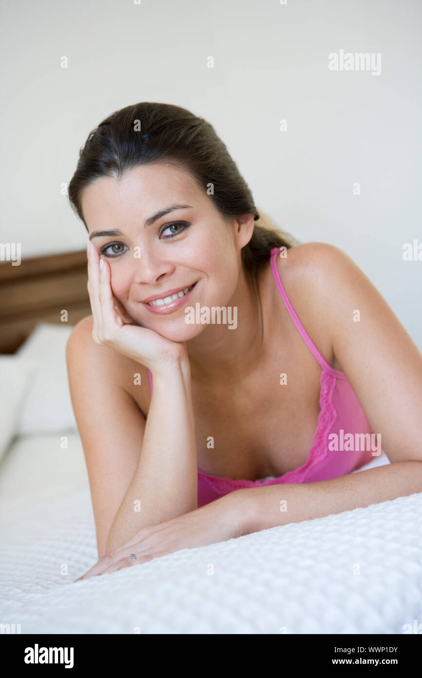 Mujer relajante en la cama en el dormitorio sonriendo (enfoque selectivo) Foto de stock