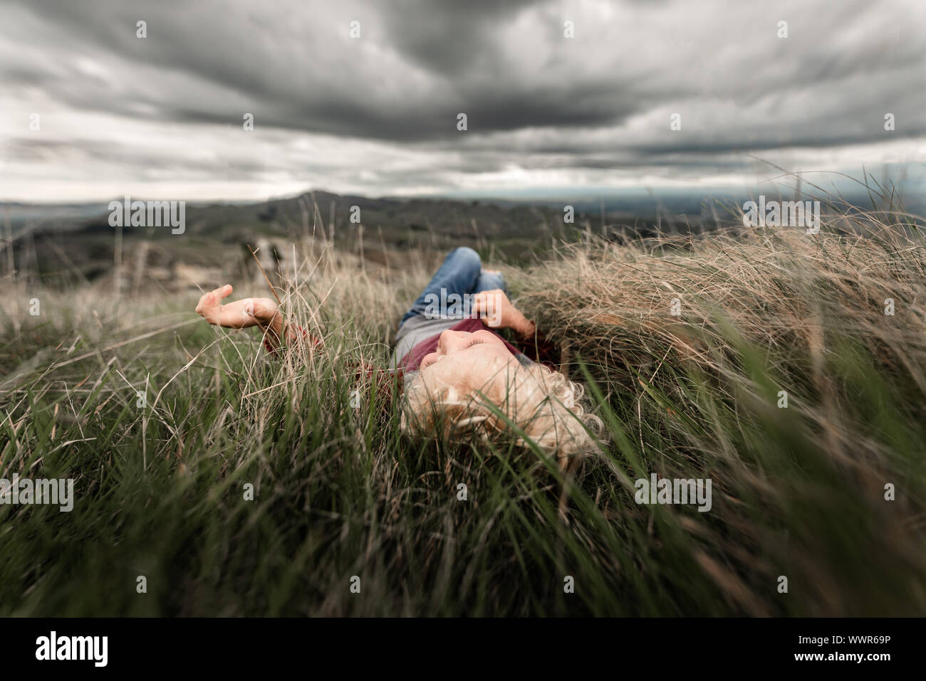 Joven acostado en el pasto alto Foto de stock