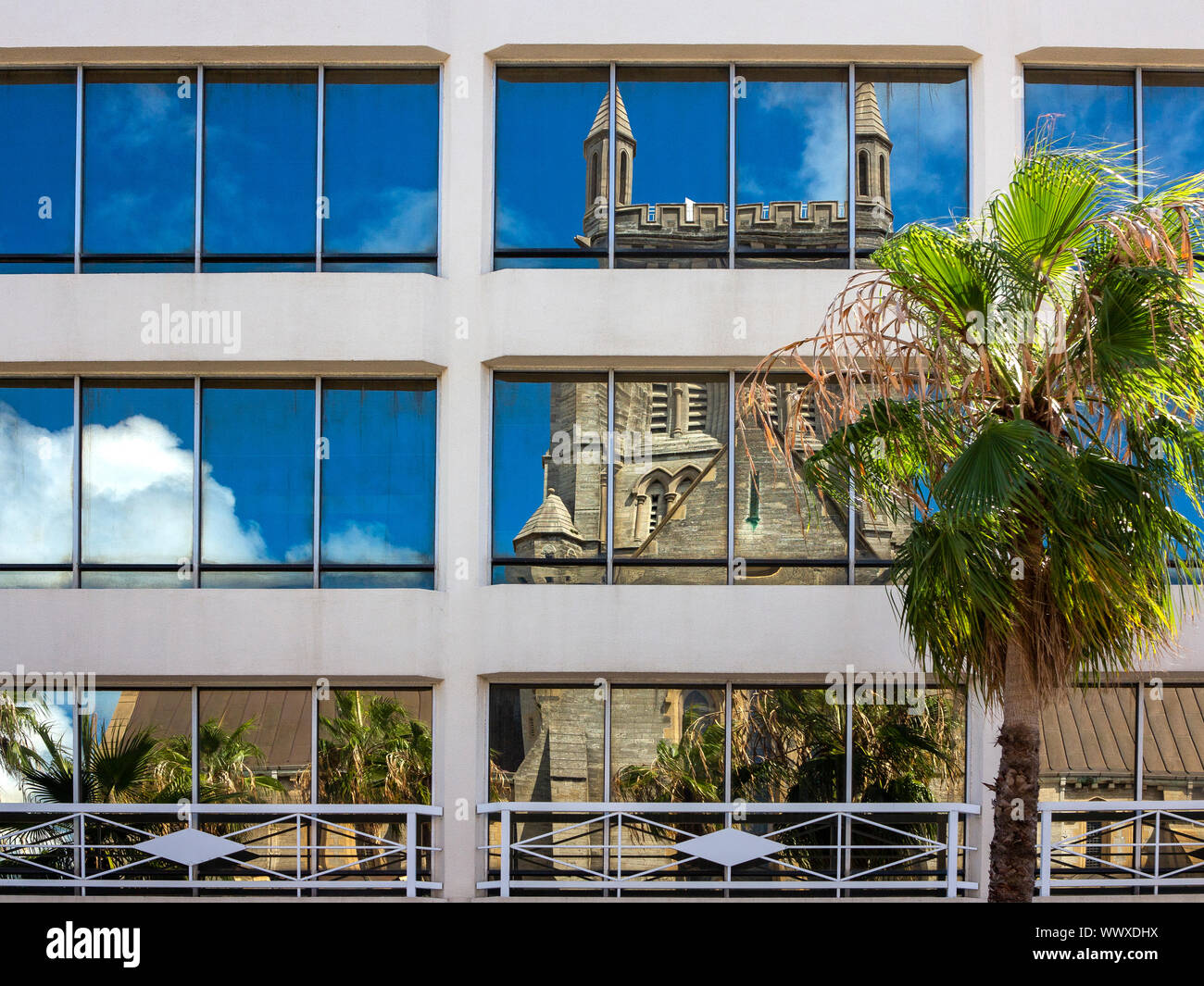 Catedral de la Santísima Trinidad, Bermudas, visto distorsionadas y reflejado en un bloque de oficinas de windows Foto de stock