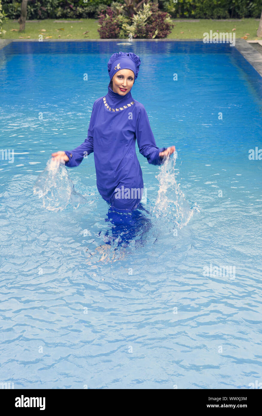 Mujer atractiva en un musulmán bañador burkini salpicaduras de agua en la  piscina Fotografía de stock - Alamy