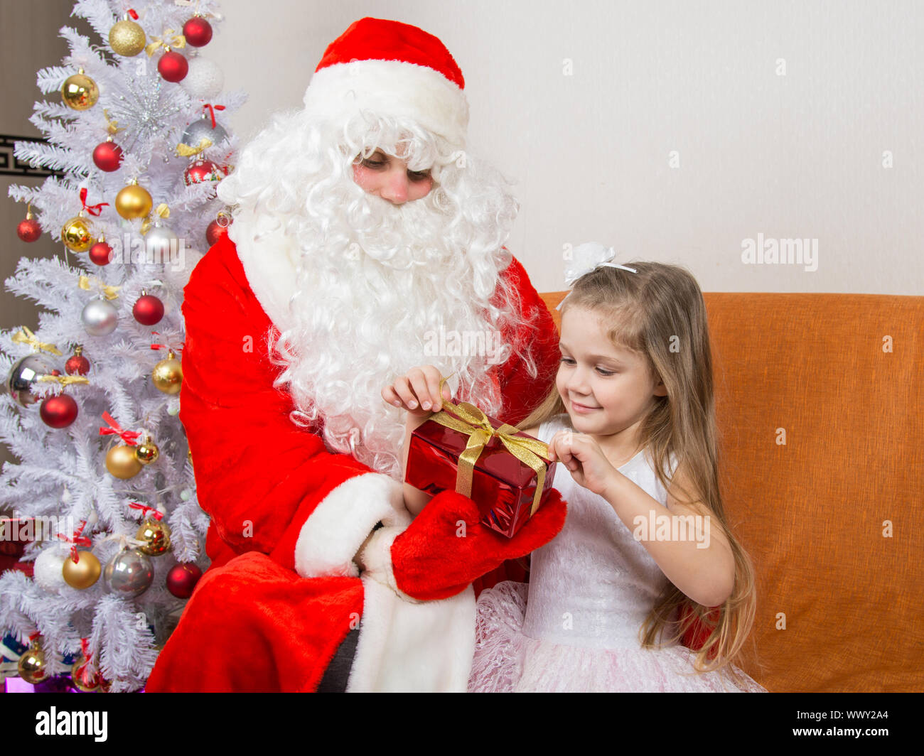 Chica desata una cinta roja regalo que sigue a Santa Claus en manos de  Fotografía de stock - Alamy