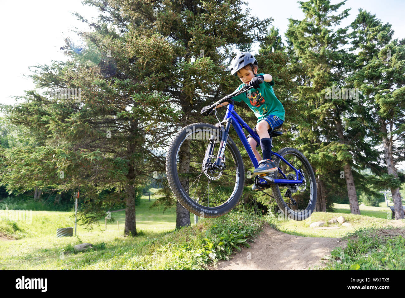 Un niño de siete años haciendo salta sobre su bicicleta de montaña Foto de stock