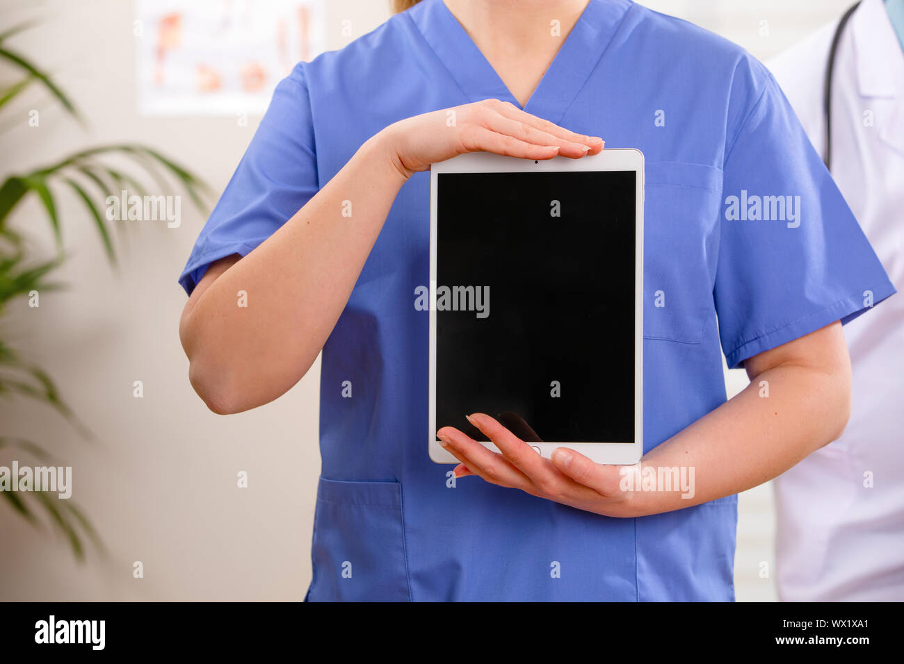 Hembra adulta de doctor o enfermera mostrando una imagen digital o un informe sobre una tableta Foto de stock
